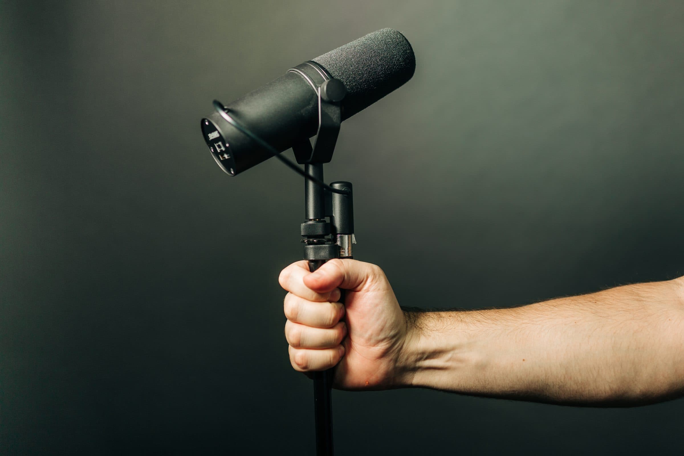 A hand gripping a microphone on its stand in the studio